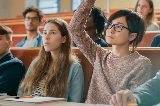 Student raising a hand in a college class.