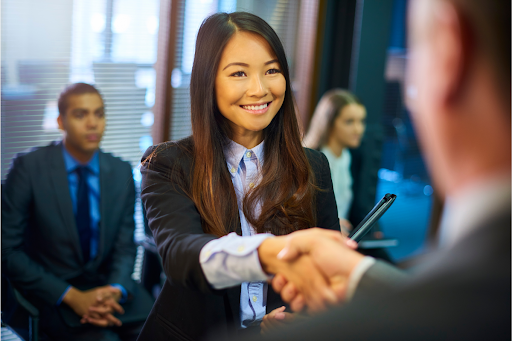 Young woman shaking hands with a man in a suit.