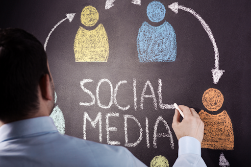 A teacher writing "SOCIAL MEDIA" on a chalkboard.