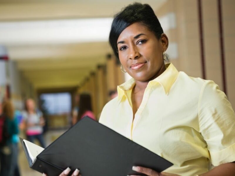 Teacher holding a lesson plan folder.