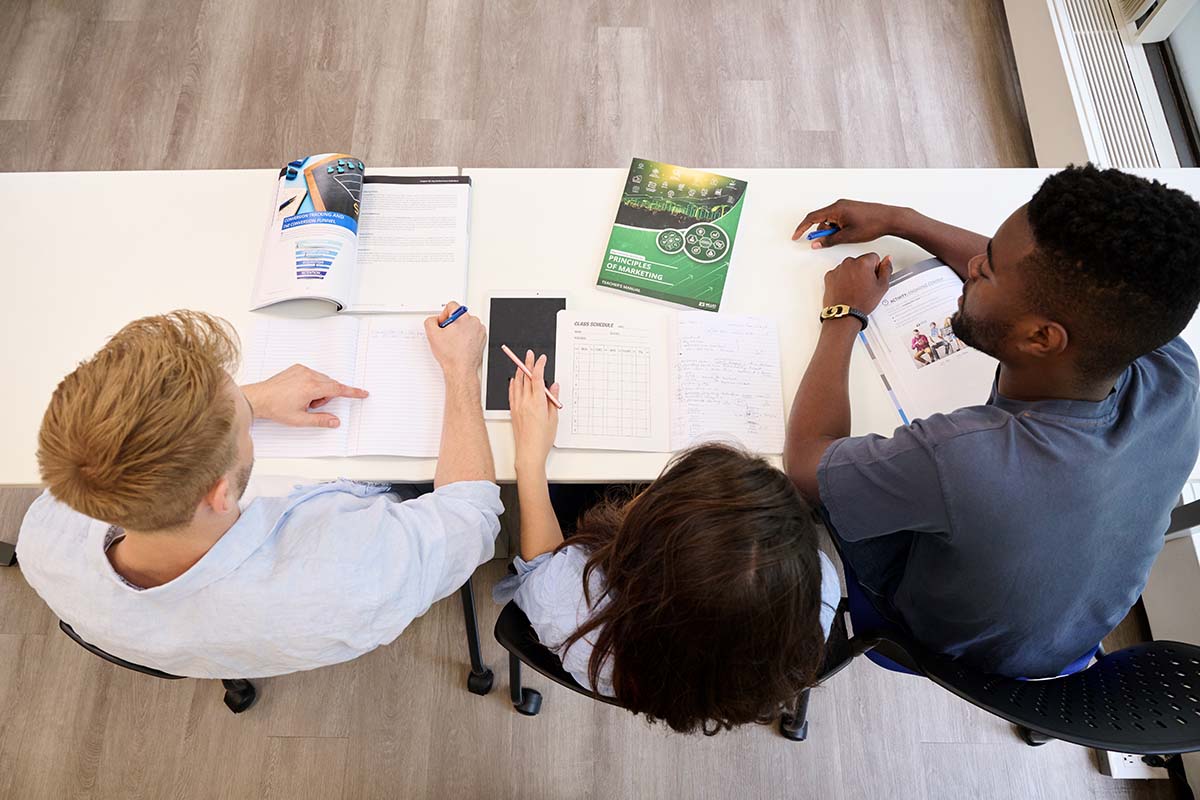 Students in a classroom with the Principles of Marketing textbook on their desk