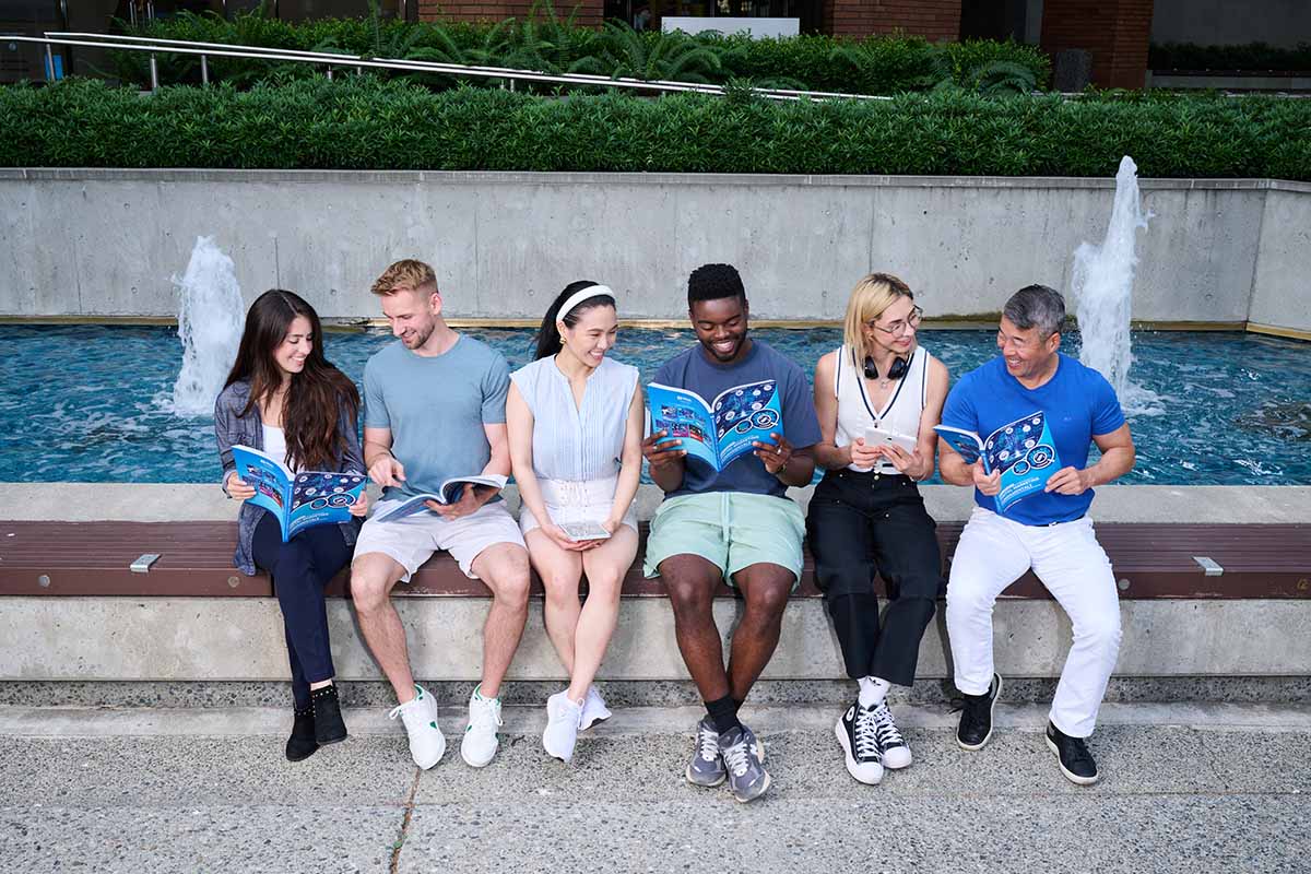 Students with Mujo Learning Systems textbooks sitting in a single row outdoors